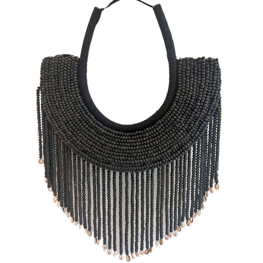 A beaded wall hanging featuring tiny black beads and cowrie shells on a macrame backing.