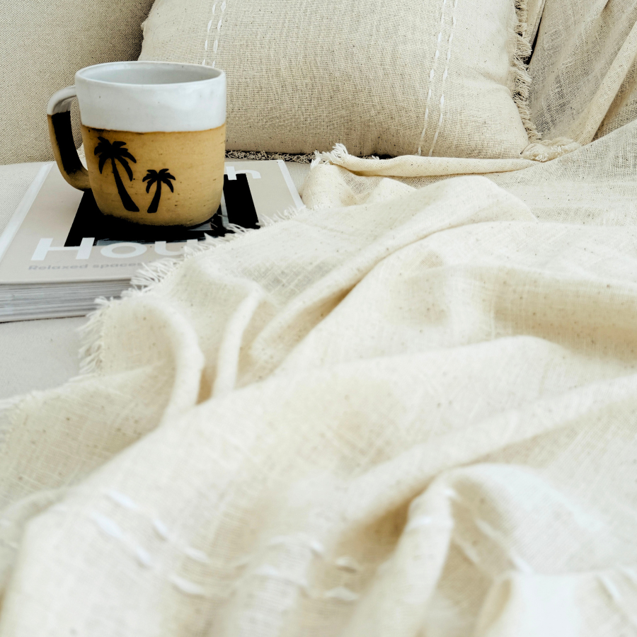 Cozy living room scene with a mug on a small table, cushion, and a blanket.