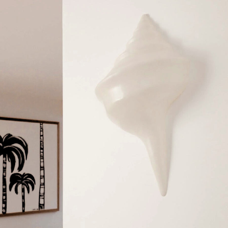 Decorative shell on a wall with a palm tree painting in the background