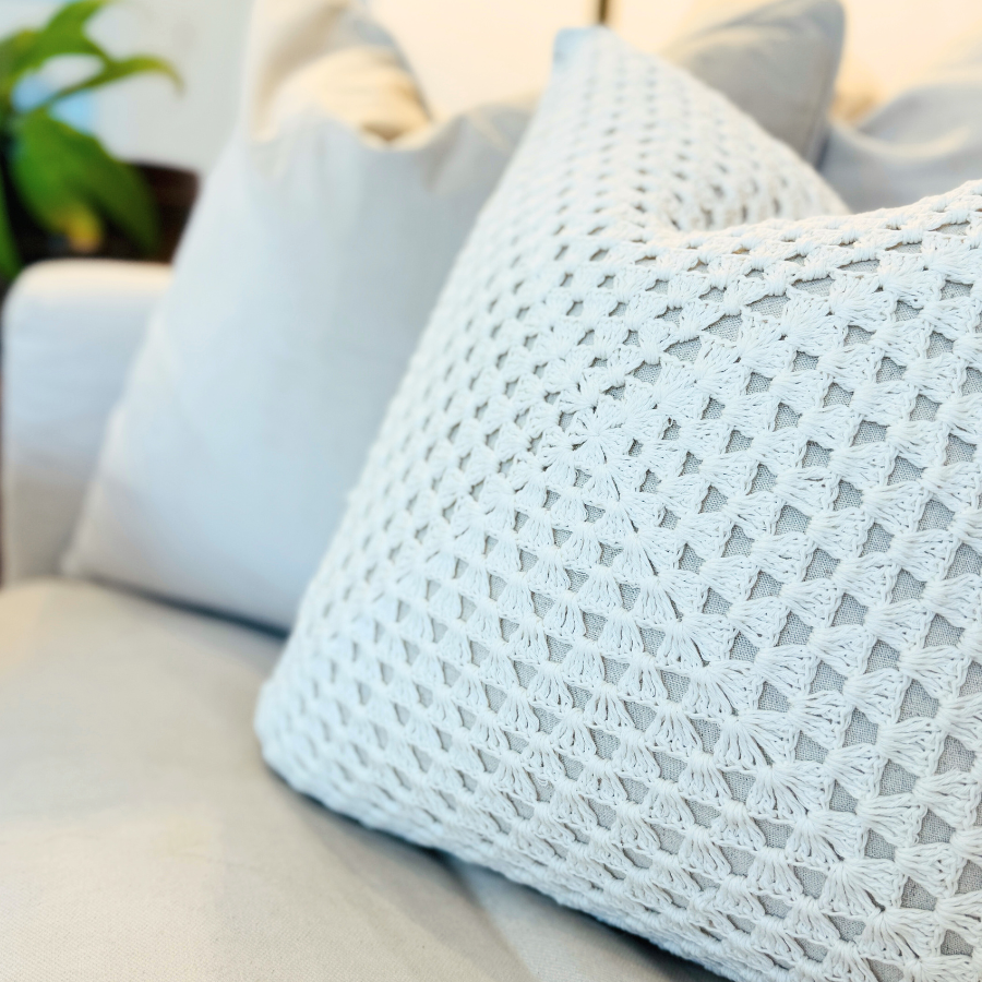 Light blue textured cushion on a beige sofa with a blurred indoor background.