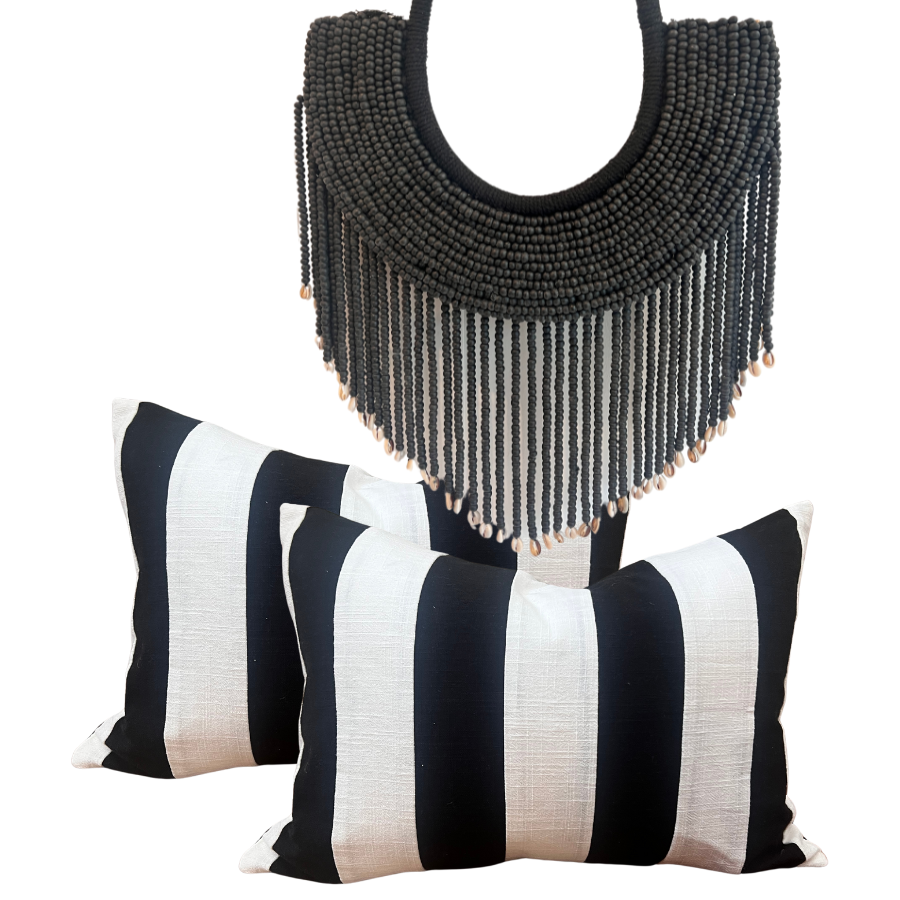 Two black and white striped linen cushions and one black timber-beaded wall hanging.