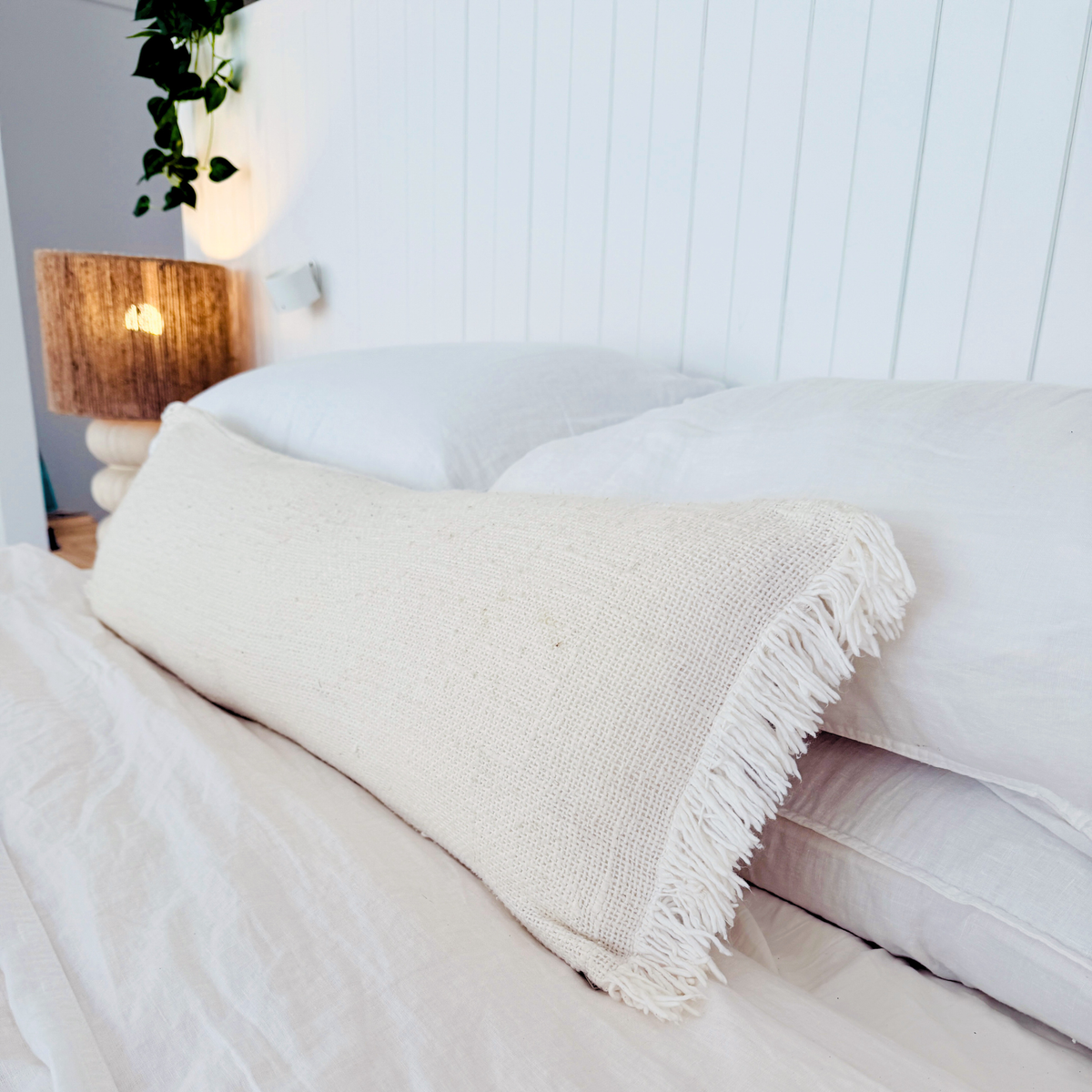 Neatly made bed with a beige throw blanket in a bedroom setting.