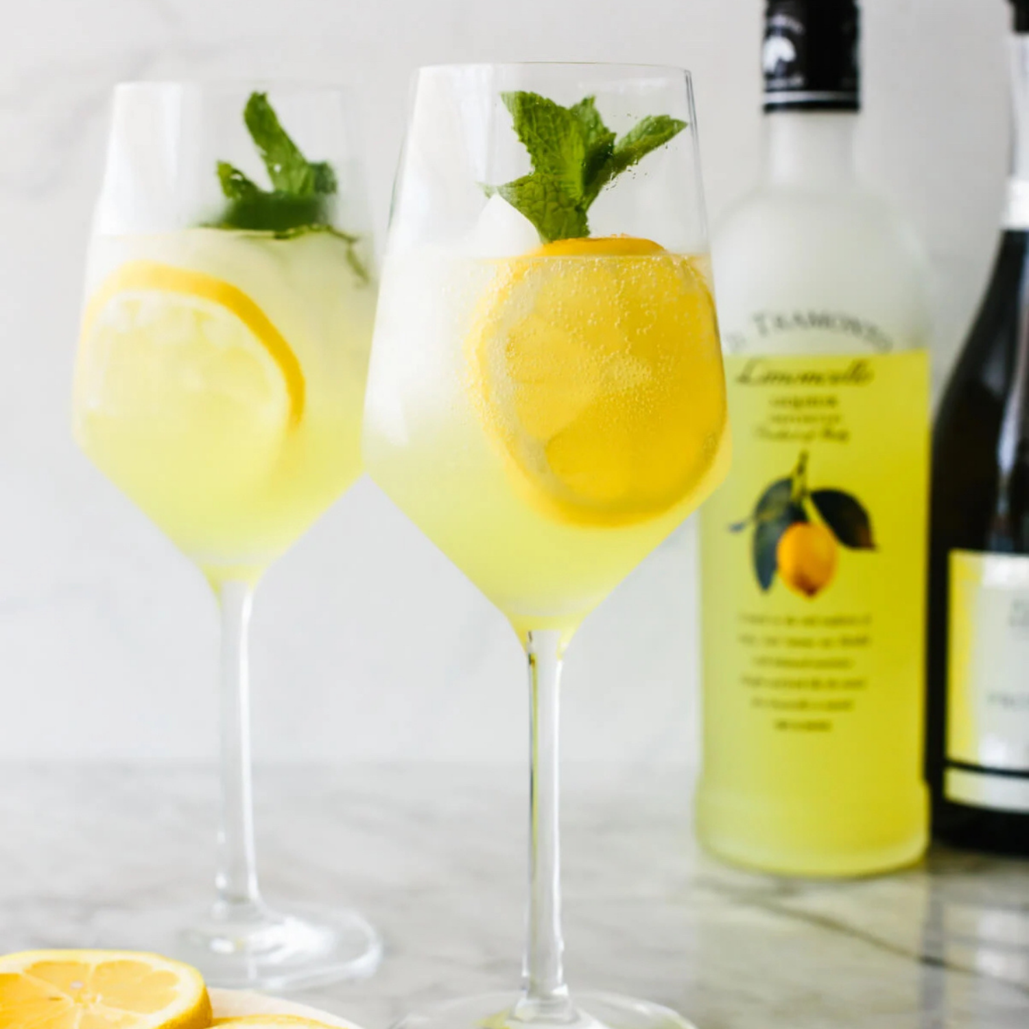 two glass of Limoncello Spritz with bottle behind and lemon