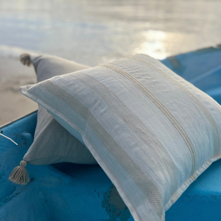 Two white cushions on a beach.