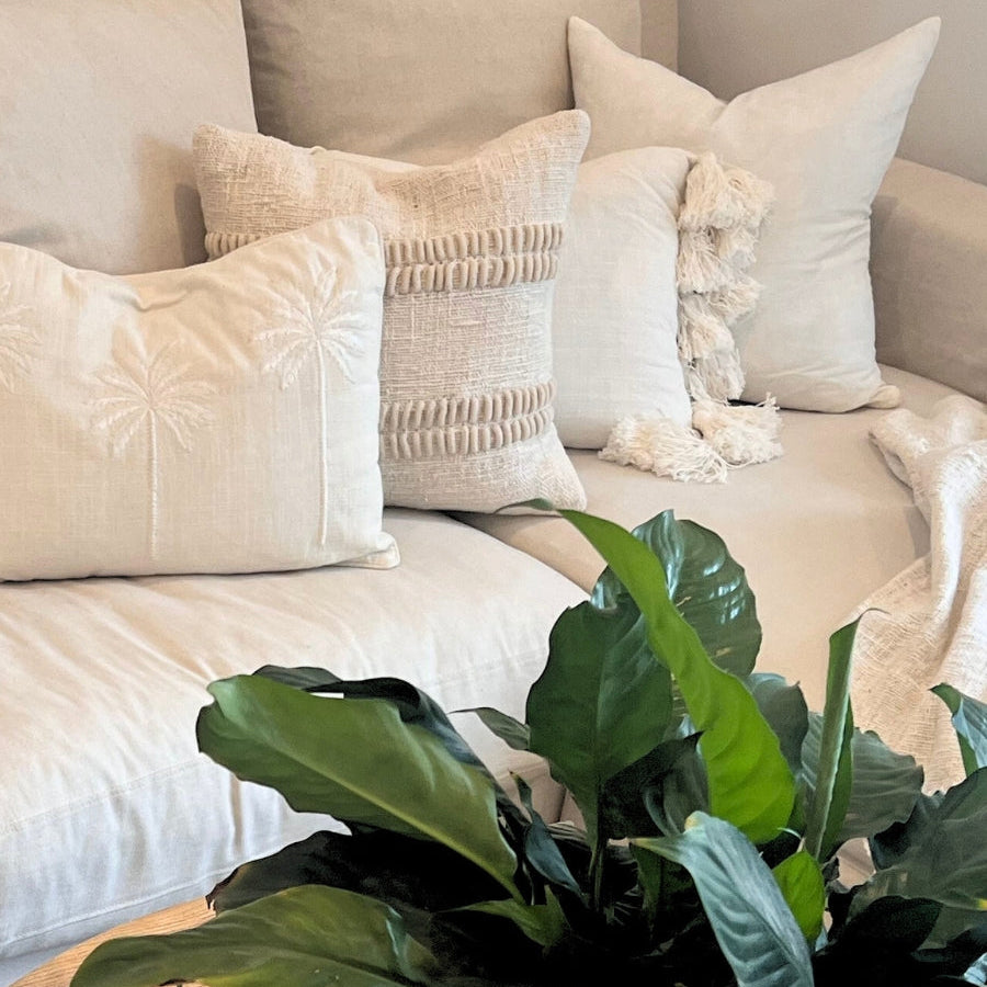 White cushions on a sofa with plant decor.