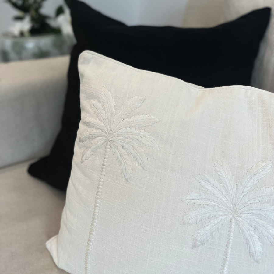 Black and white cushion with palm tree decor.