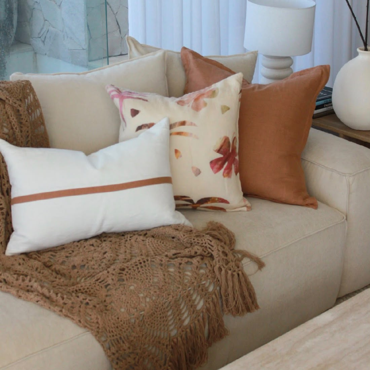 Cinnamon and palm print linen cushion set with a brown throw on a sofa.
