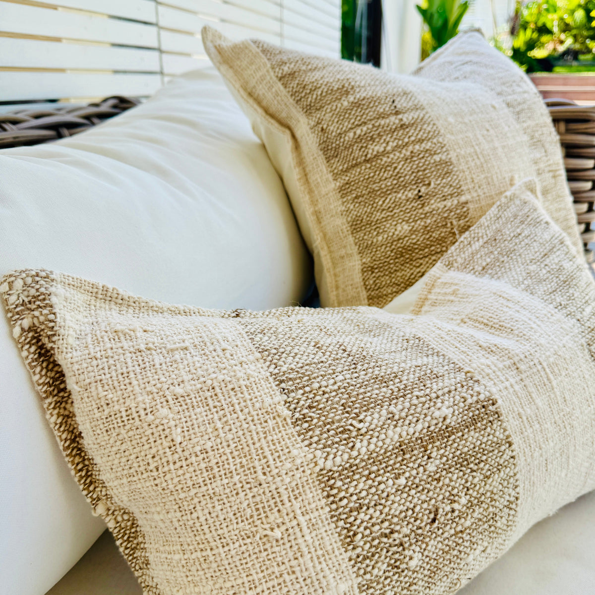 Textured neutral woven throw cushions styled on an outdoor sofa.