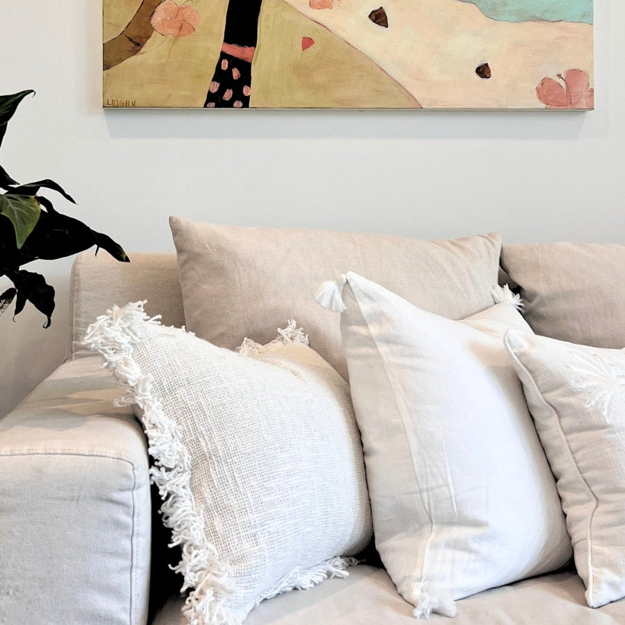 White cushions on a sofa with painting. 