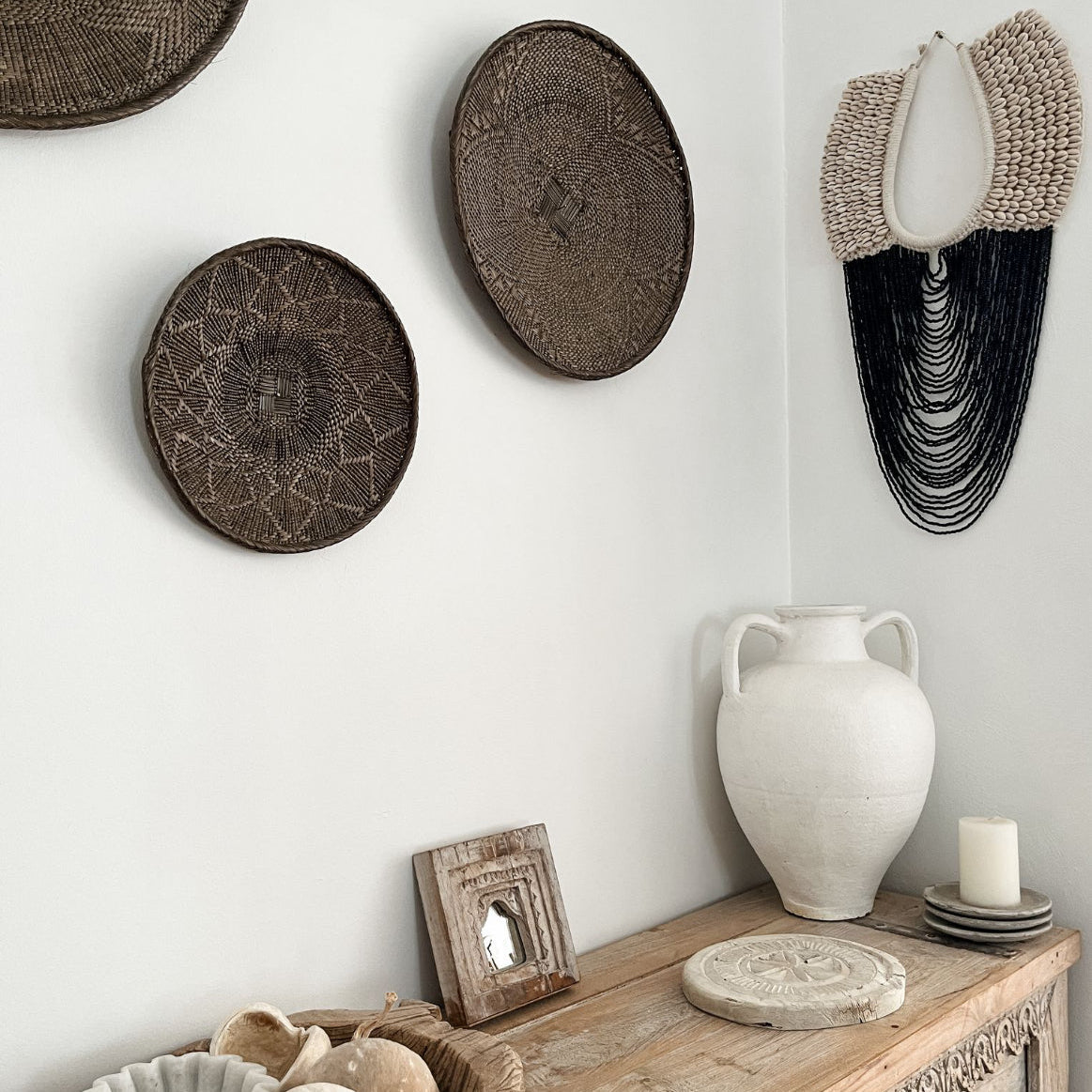 Beaded wall decor with woven decor and vases.