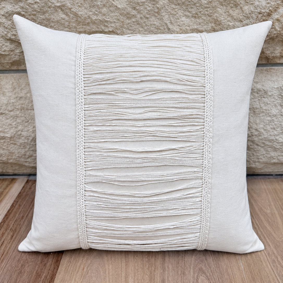 Square cream linen throw cushion featuring a center woven fringe tassel overlay.