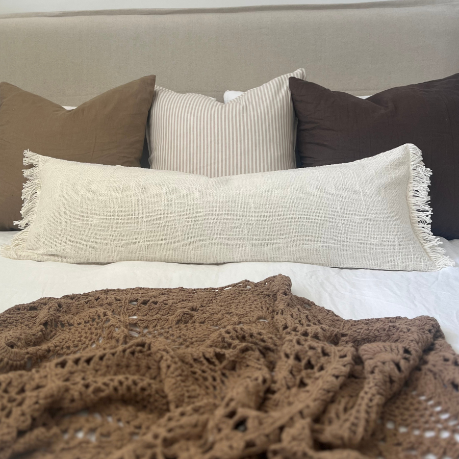 Cushions and blanket on a bed. 