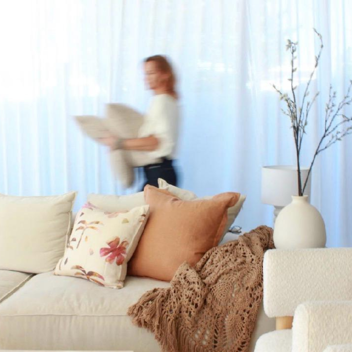 Palm print pillow, cinnamon cushion, and woven mocha throw styled on a neutral sofa.