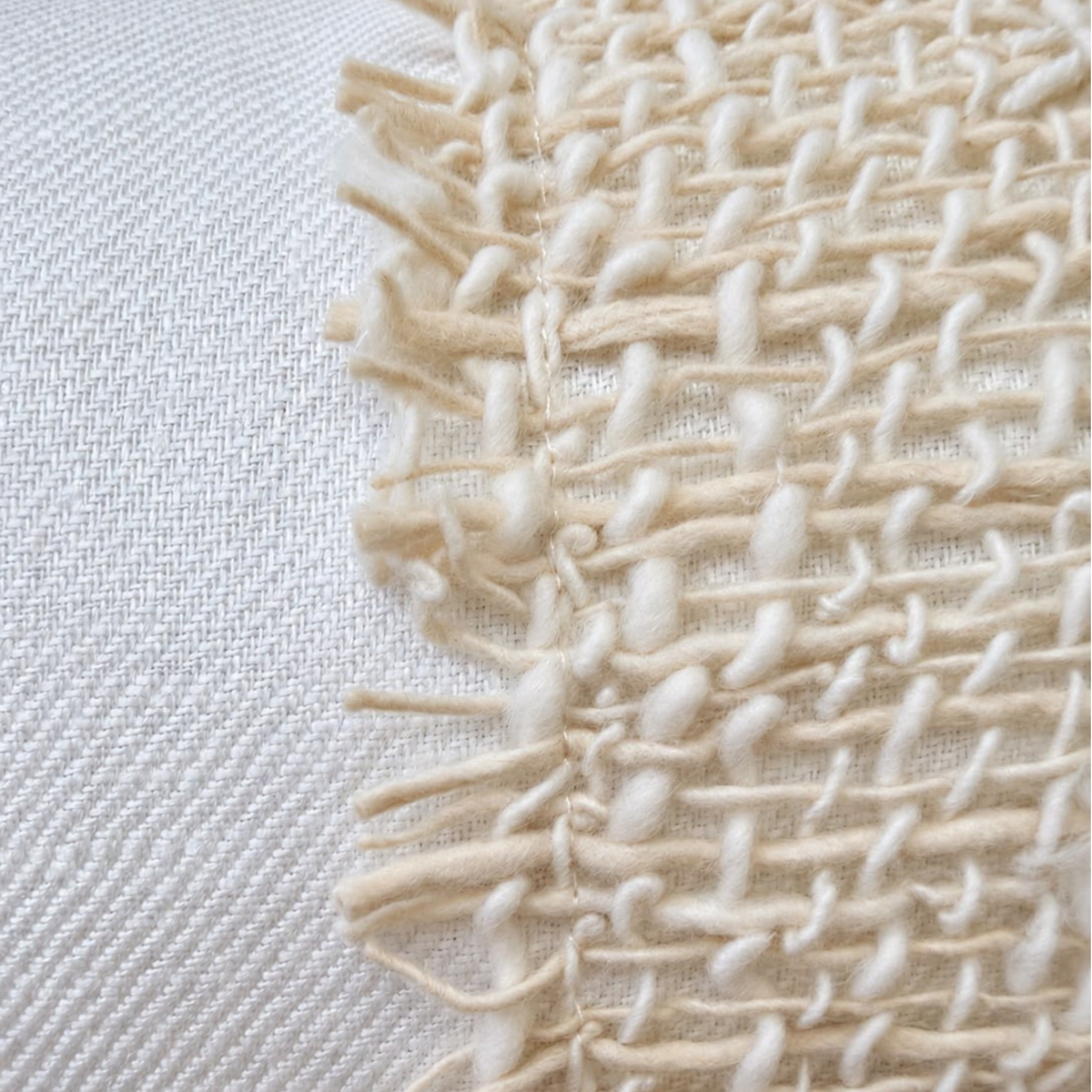 Macro detail showing fray fringe raw edges and chunky woven texture on white linen.