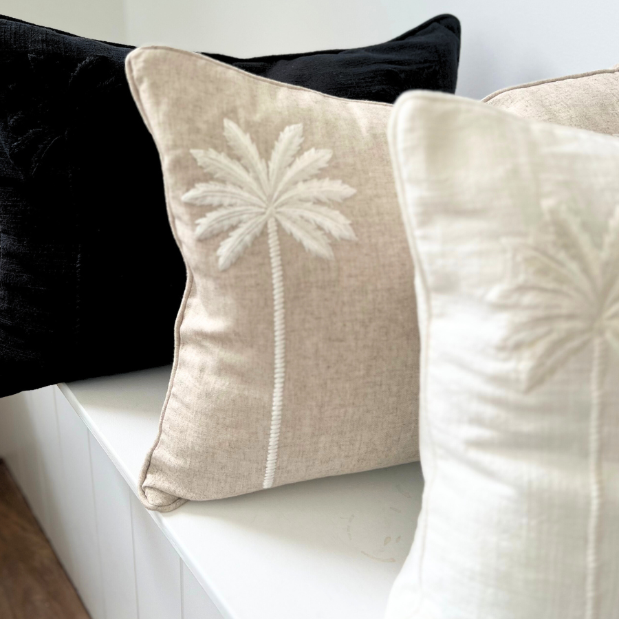 black and white cushions with palm tree decor on a sofa.