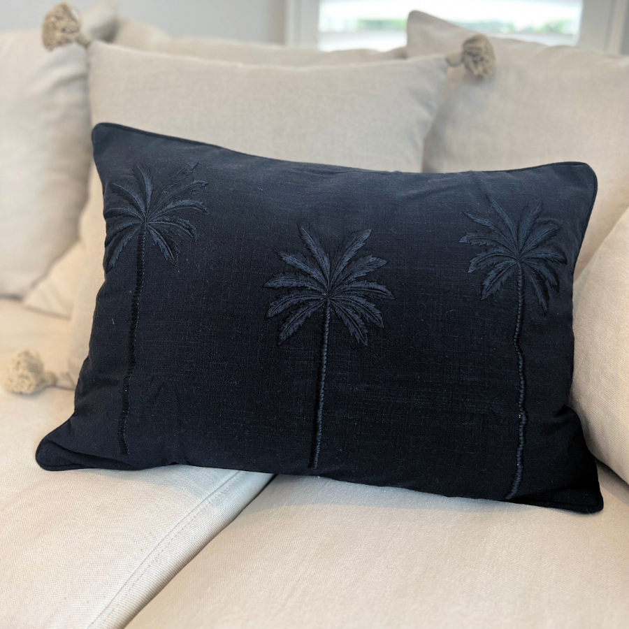 Black and white cushion with palm tree decor.