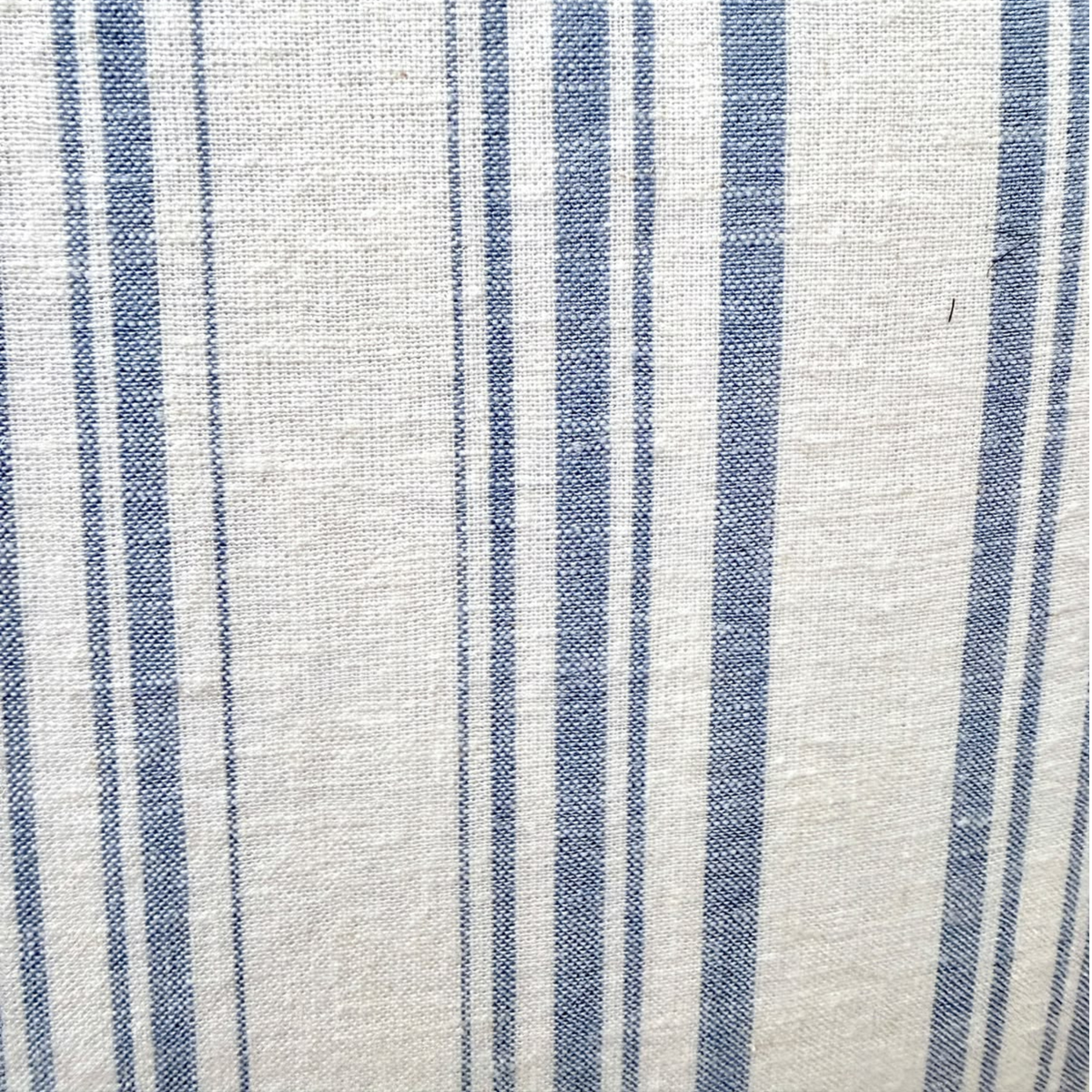 Close-up detail of natural woven white linen fabric featuring fine blue vertical stripes.
