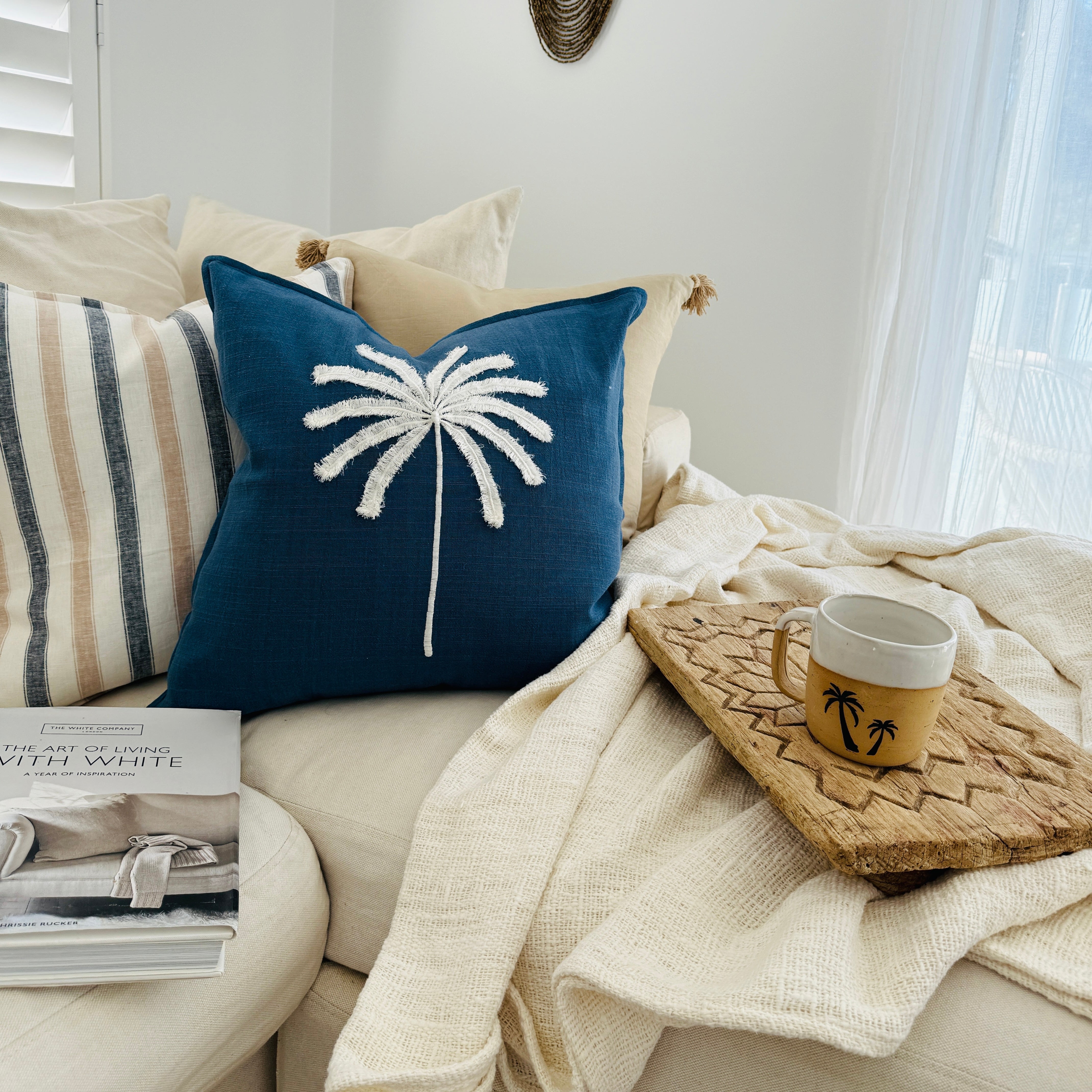 Nautical-themed cushion with palm tree design on a cozy living room sofa.