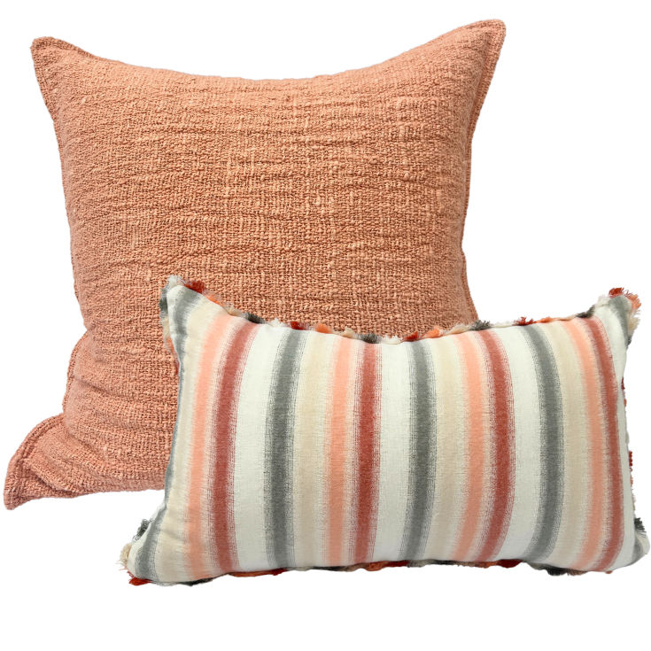 Two decorative cushion, one peach-colored and one striped.