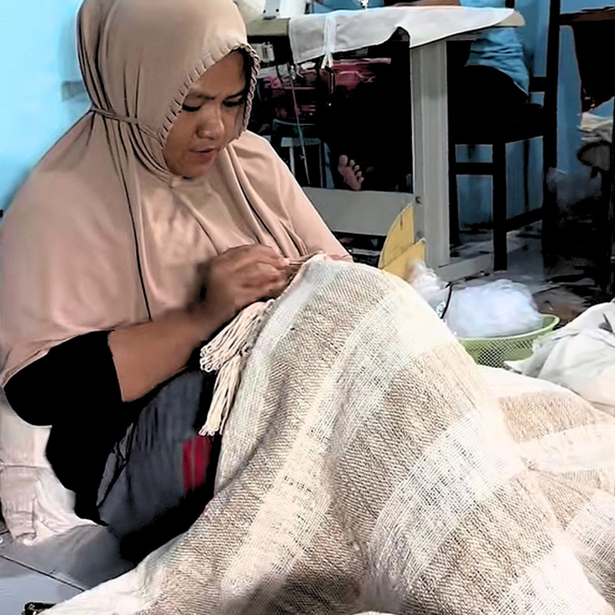 Woman working on a piece of fabric in a workshop setting.
