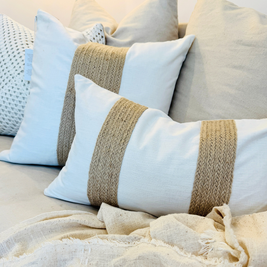 Decorative cushion with jute ribbon on a bed with a beige blanket