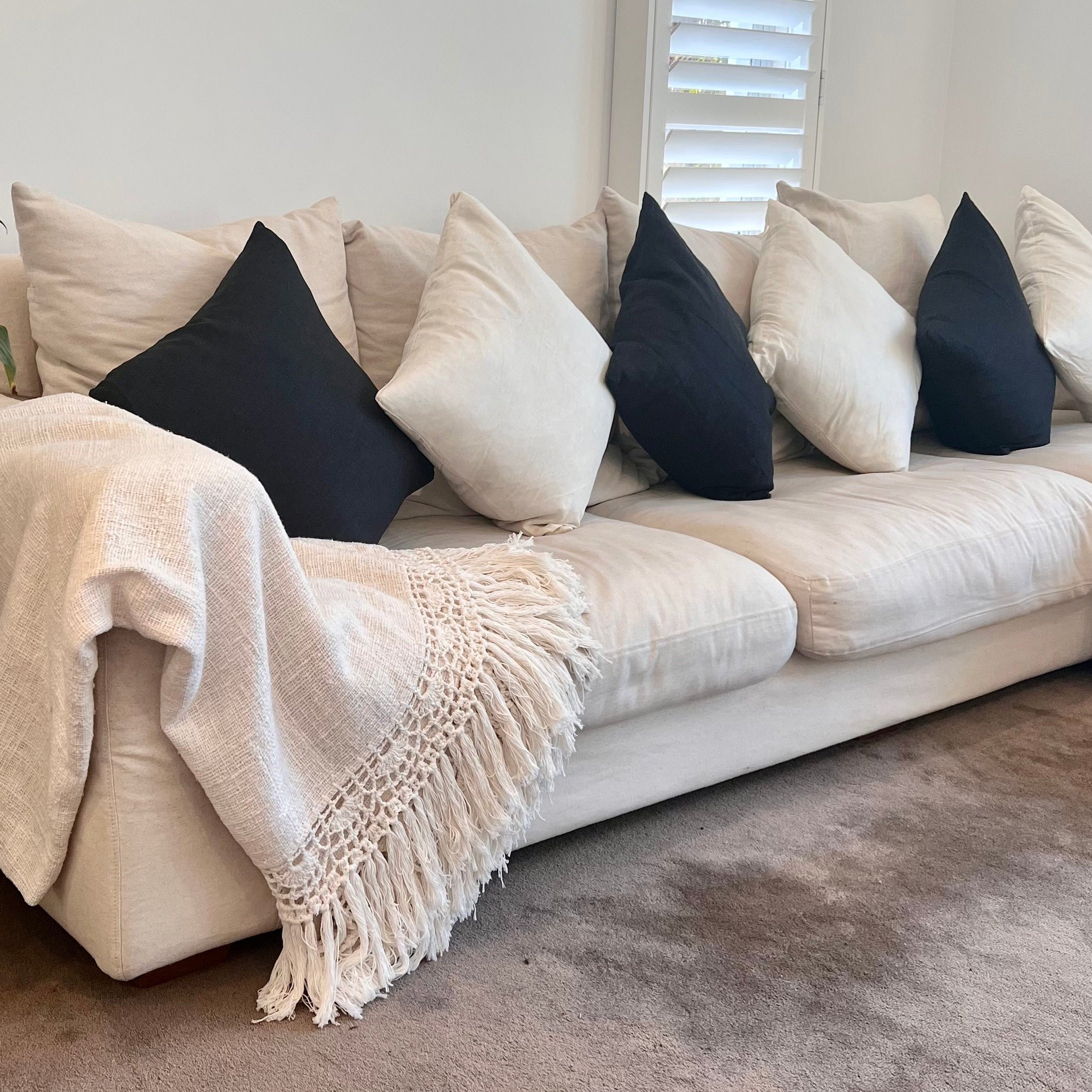 White and blue cushions on a sofa with blanket. 